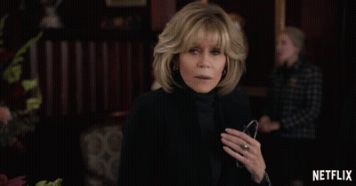 A Woman With A Ring On Her Finger Stands In Front Of A Netflix Ad GIF
