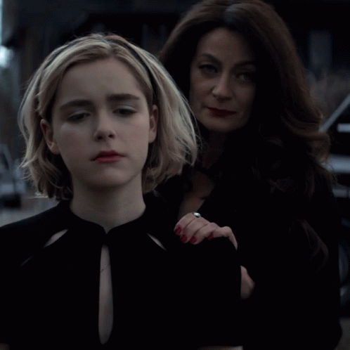 A Woman With A Ring On Her Finger Stands Next To A Girl GIF