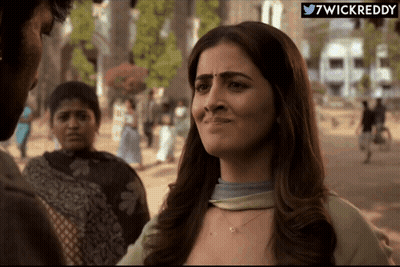 A Woman With A Sad Look On Her Face Is Standing In Front Of A Sign That Says ' 7Wickreddy ' On It GIF