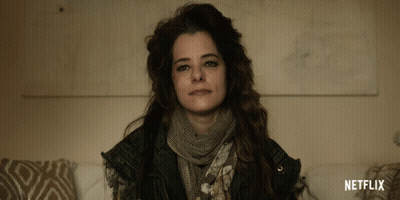 A Woman With A Scarf Around Her Neck And A Netflix Logo On The Bottom GIF