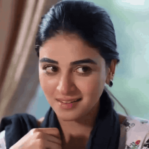 A Woman With A Scarf Around Her Neck Is Smiling GIF