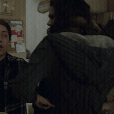 A Woman With A Scarf Around Her Neck Stands Next To Another Woman In A Kitchen GIF