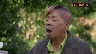 A Woman With A Shaved Head And A Green Shirt Is Yawning With Her Mouth Open . GIF