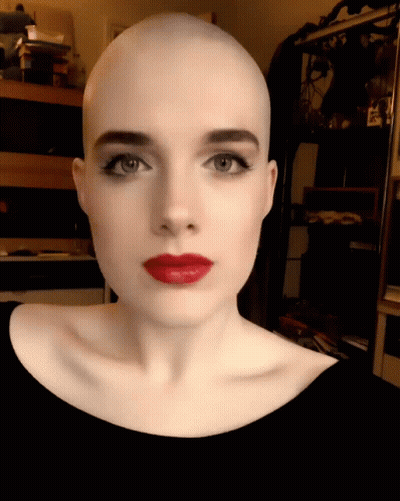 A Woman With A Shaved Head And Red Lips GIF