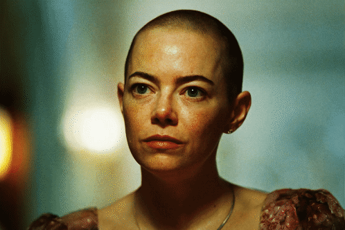 A Woman With A Shaved Head Is Wearing A Dress GIF