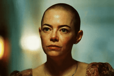 A Woman With A Shaved Head Is Wearing Earrings GIF