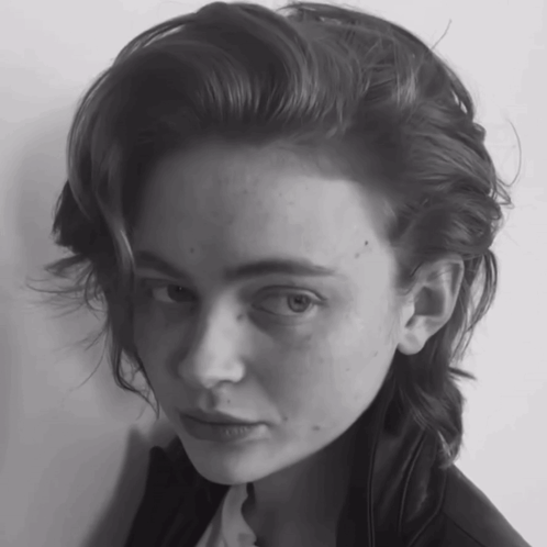 A Woman With A Shaved Head Looks At The Camera In A Black And White Photo GIF