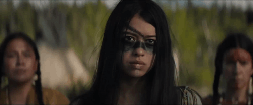 A Woman With A Skull Painted On Her Face Is Standing In Front Of Two Native American Women . GIF