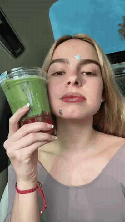 A Woman With A Star Tattoo On Her Forehead Is Holding A Cup Of Green Tea . GIF