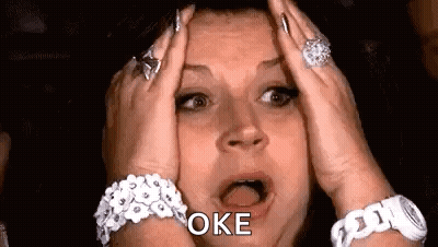 A Woman With A Surprised Look On Her Face Is Holding Her Head In Her Hands . GIF