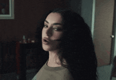 A Woman With A Surprised Look On Her Face Is Standing In A Dark Room GIF