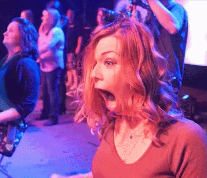 A Woman With A Surprised Look On Her Face Is Standing In Front Of A Crowd GIF