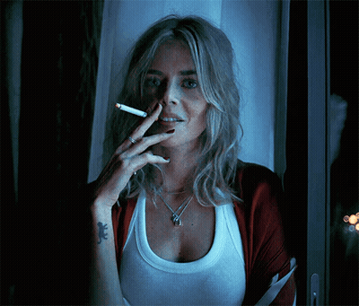 A Woman With A Tattoo Of A Lizard On Her Wrist Smoking A Cigarette GIF