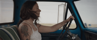 A Woman With A Tattoo On Her Arm Is Driving A Truck GIF