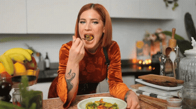 A Woman With A Tattoo On Her Arm Is Eating A Meal GIF