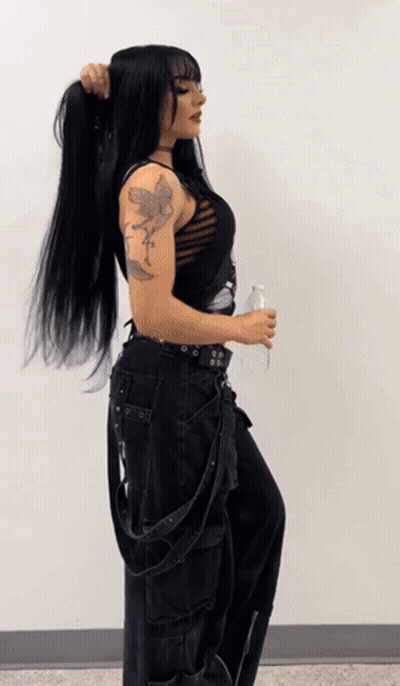 A Woman With A Tattoo On Her Arm Is Holding A Bottle Of Water GIF