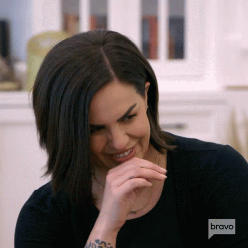 A Woman With A Tattoo On Her Arm Is Laughing With A Bravo Logo Behind Her GIF
