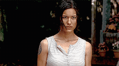 A Woman With A Tattoo On Her Arm Is Standing In A Dark Room GIF