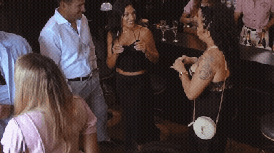 A Woman With A Tattoo On Her Arm Is Talking To A Man In A White Shirt GIF