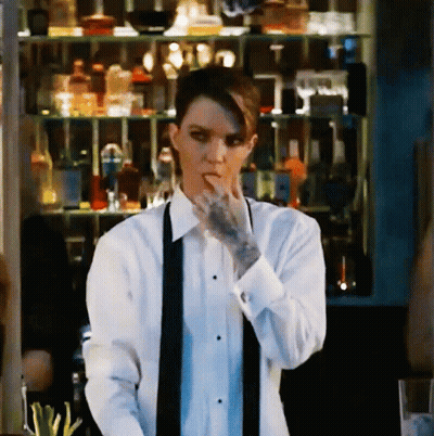 A Woman With A Tattoo On Her Arm Is Wearing A Tuxedo And A Black Tie GIF