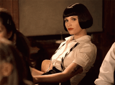A Woman With A Tattoo On Her Arm Is Wearing A White Shirt And Black Tie GIF