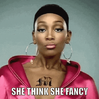 A Woman With A Tattoo On Her Chest Is Wearing A Pink Jacket And Hoop Earrings And Says She Think She Fancy GIF