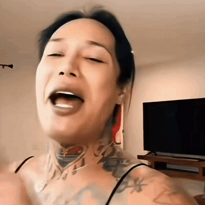 A Woman With A Tattoo On Her Neck Has Her Eyes Closed And Her Tongue Out GIF
