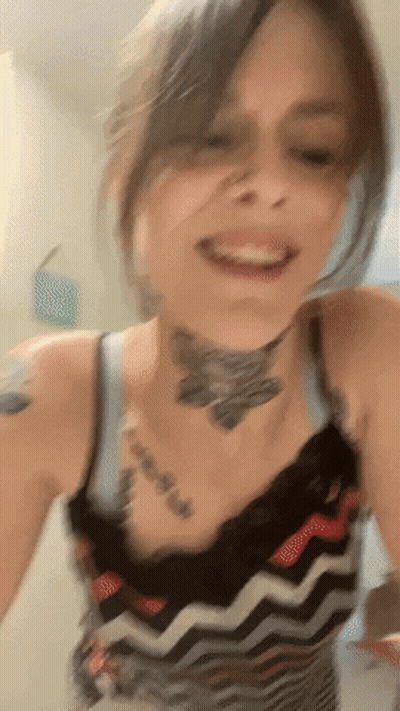 A Woman With A Tattoo On Her Neck Is Smiling And Looking At The Camera GIF