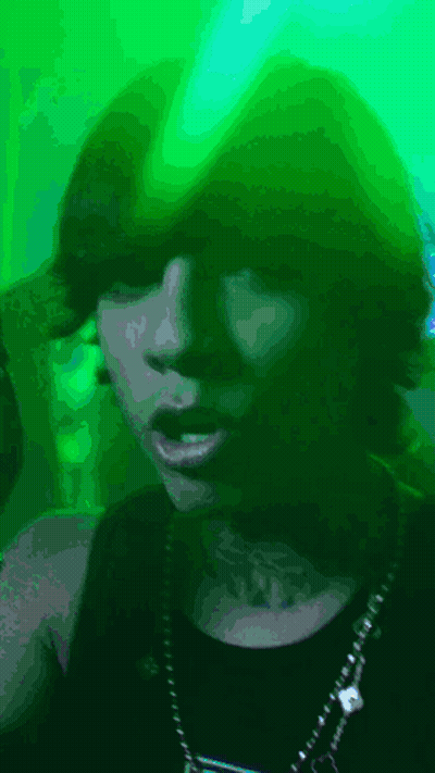 A Woman With A Tattoo On Her Neck Is Wearing A Green Hat GIF