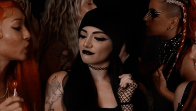A Woman With A Tattoo On Her Shoulder Is Smiling In A Crowd Of People GIF