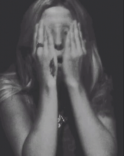 A Woman With A Tattoo On Her Wrist Covering Her Face GIF