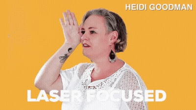 A Woman With A Tattoo On Her Wrist Is Wearing A White Shirt And Earrings And Says Laser Focused GIF