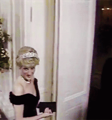 A Woman With A Tiara On Her Head Is Standing In A Doorway GIF