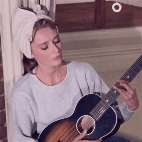 A Woman With A Towel Around Her Head Is Playing A Guitar GIF