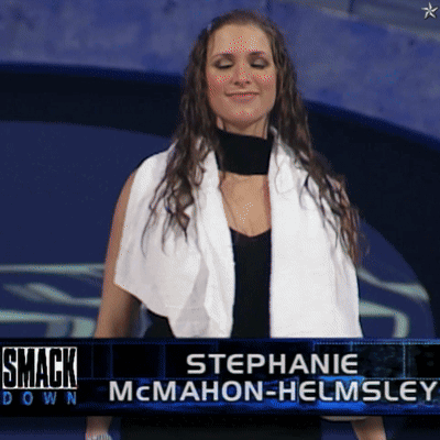 A Woman With A Towel Around Her Neck Is Standing In Front Of A Smack Down Sign GIF