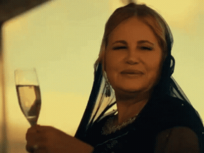 A Woman With A Veil On Her Head Is Holding A Glass Of Wine GIF
