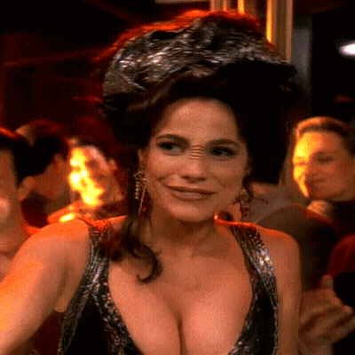 A Woman With A Very Large Breast Is Wearing A Very Revealing Dress . GIF