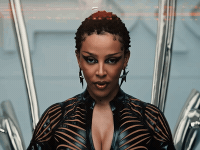 A Woman With A Very Plunging Neckline And A Star Earring Looks At The Camera GIF