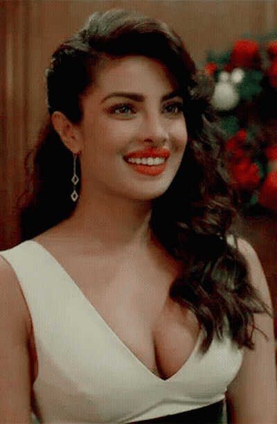 A Woman With A Very Plunging Neckline Is Smiling And Wearing Red Lipstick GIF
