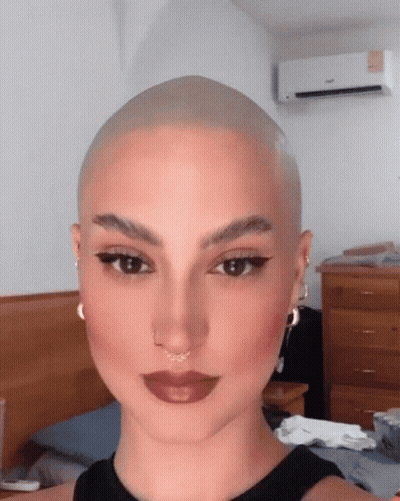 A Woman With A Very Shaved Head Is Wearing A Black Tank Top GIF