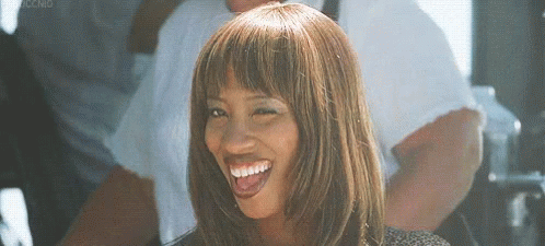 A Woman With A Wig And Bangs Is Smiling . GIF