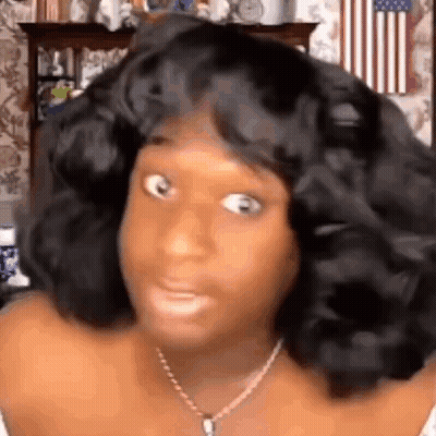 A Woman With A Wig On Her Head Is Making A Funny Face . GIF