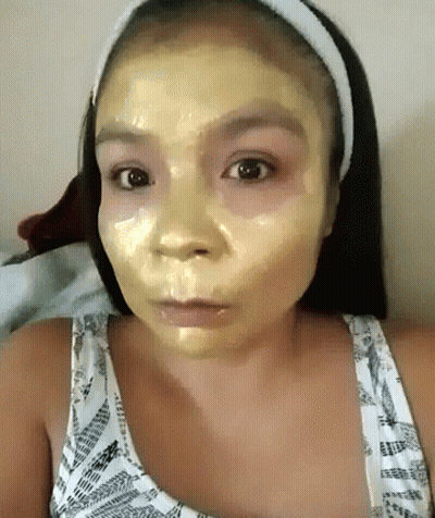 A Woman With A Yellow Mask On Her Face Looks At The Camera GIF