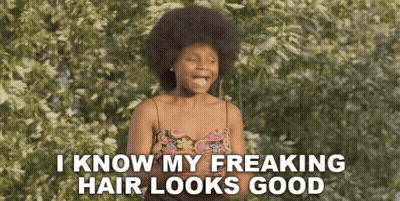 A Woman With An Afro Is Standing In Front Of A Tree And Says I Know My Freaking Hair Looks Good . GIF