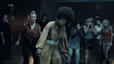 A Woman With An Afro Stands In Front Of A Crowd Of Women GIF