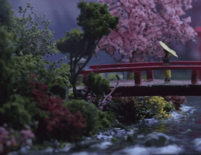 A Woman With An Umbrella Is Walking Across A Bridge GIF