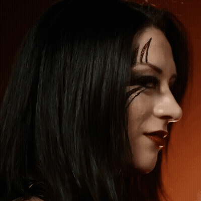 A Woman With Black Hair And Red Lips Has A Tattoo On Her Face . GIF
