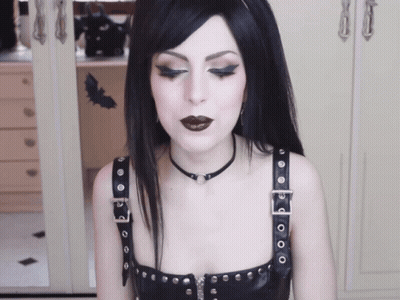 A Woman With Black Hair Wearing A Choker And A Black Top GIF