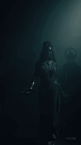 A Woman With Black Paint On Her Face Is Standing In A Dark Room With Her Arms Outstretched GIF
