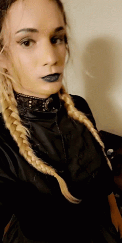 A Woman With Blonde Braids Is Wearing A Black Top GIF